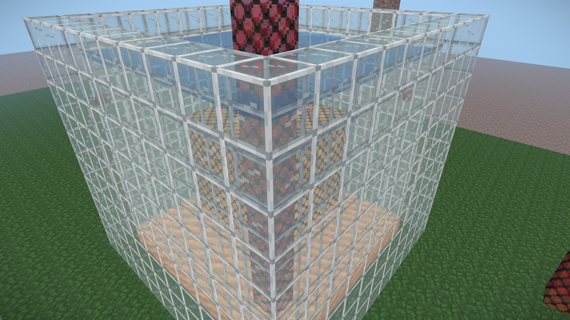 A glass tank of water with a hollow amber box sunk in it and a red glass column rising through the surface